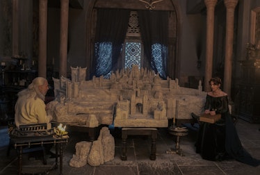 King Viserys I Targaryen (Paddy Considine) and Alicent Hightower (Emily Carey) sit near a model recr...