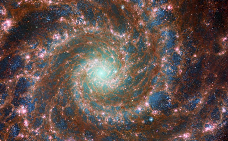 color photo of the center of a spiral galaxy, with bright star cluster in the middle and spiral arms...