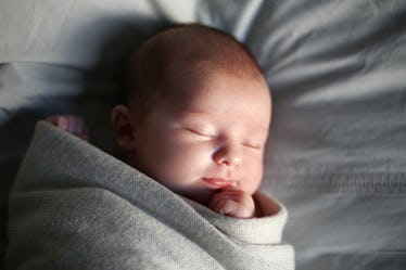 A 1-month-old new born sleeping while swaddled.