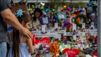 Seth Garza pays his respects with his daughter Lilly at a memorial dedicated to the 19 children and ...
