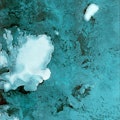 Satellite shot of the Barents Sea and Svalbard archipelago in rich teals and blues.