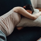 A stressed pregnant woman naps on a couch.