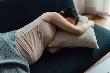 A stressed pregnant woman naps on a couch.