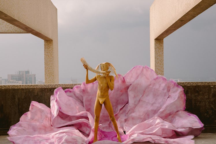 a person painted gold standing in a pink cloth shell