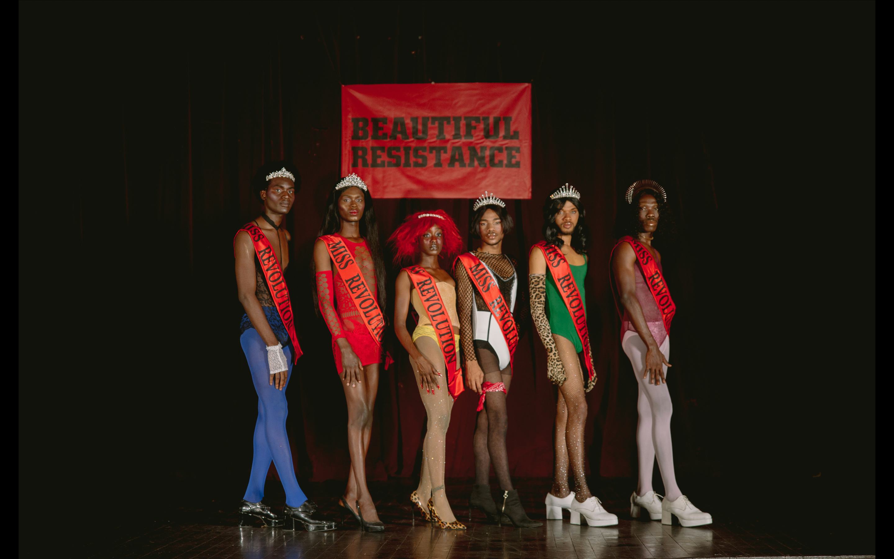 A photo of a group of pageant queens wearing 'Miss Revolution' sashes on stage.