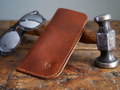 Light brown leather glasses case is a great grandparents day gift. The case is posed on top of a ham...