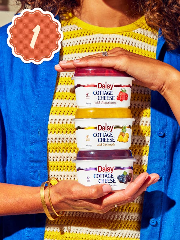 Woman holding three Daisy Cottage Cheeses. One with strawberry, one with pineapple and the third wit...