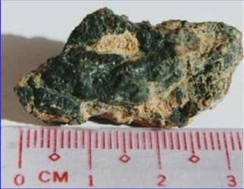 color photo of a multicolored rock next to a ruler, measuring 3 centimeters