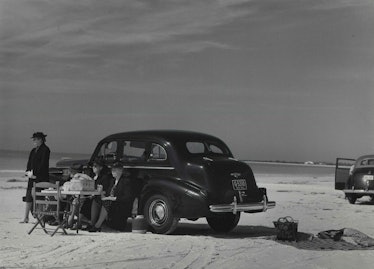 A black-and-white photo of a car on the beach