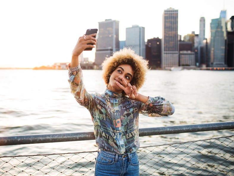 Young woman throwing up the peace sign on her ideal solo travel destination trip, based on her zodia...