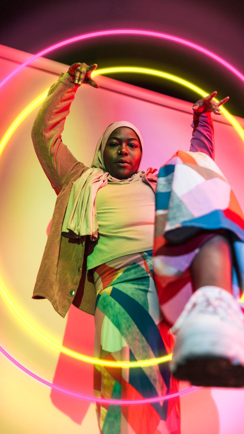 Young woman stomping her foot in front of a multi-colored studio background during the last supermoo...