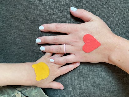 Diese einfach anzuwendenden Pflaster beruhigen Insektenstiche und gereizte Haut bei Kindern 1 Die Hände eines Kindes und eines Elternteils, mit einem der beruhigenden Patches von EmBaba auf jeder Hand.