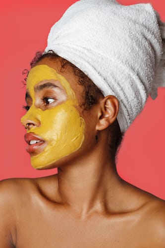 A lady with a yellow glow-boosting turmeric mask on her face