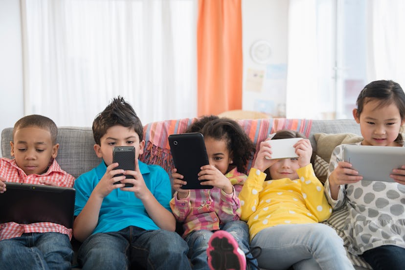 Children on a couch looking at smart phones and devices.