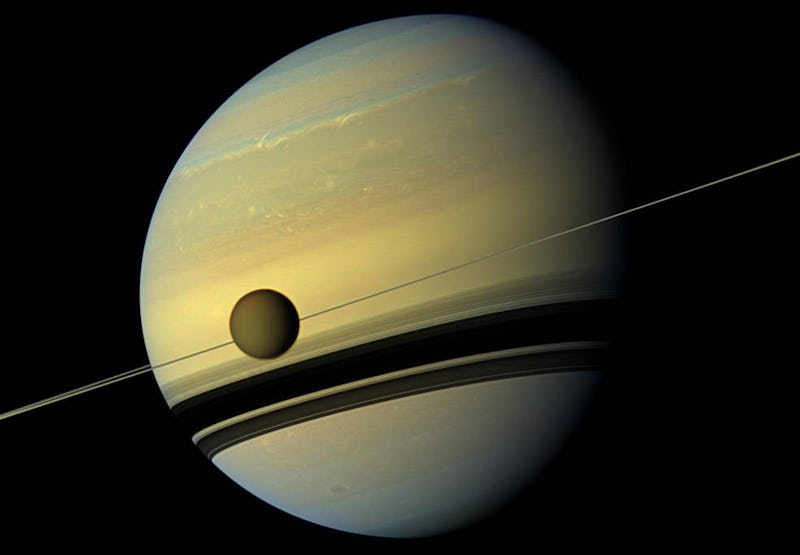 titan crosses saturn with the rings seen edge-on