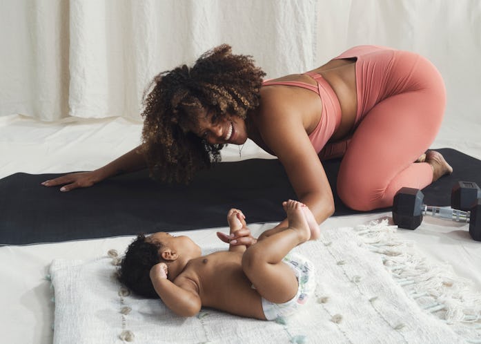 Mother doing yoga and strength training while she watches over her baby