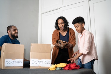 A child helps his parents pack clothes for donation into boxes.