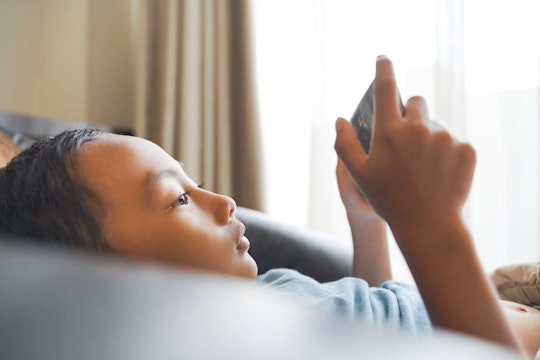 What are the best smart phones and devices for kids? A little boy is shown laying down looking at a ...