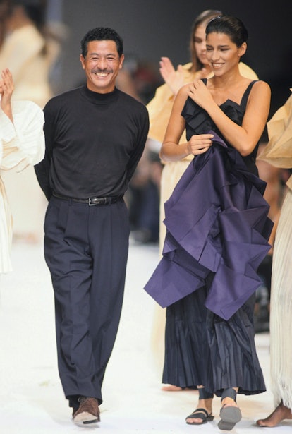 Issey Miyake, the Japanese designer standing on the runway next to a model wearing his design