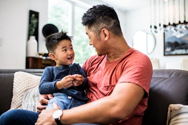 A dad talking to his son on a couch.