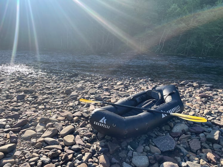 The Kokopelli Rogue-Lite X Packraft placed on the rocky shore next to a river