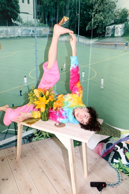 A person wearing a tie dye shirt lifting their leg up in the air