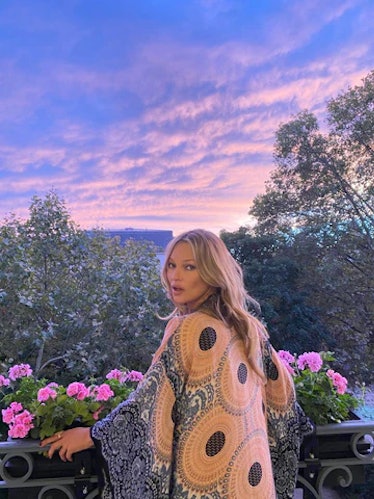 Kate Moss looking over her shoulder against the backdrop of a pink and purple sky
