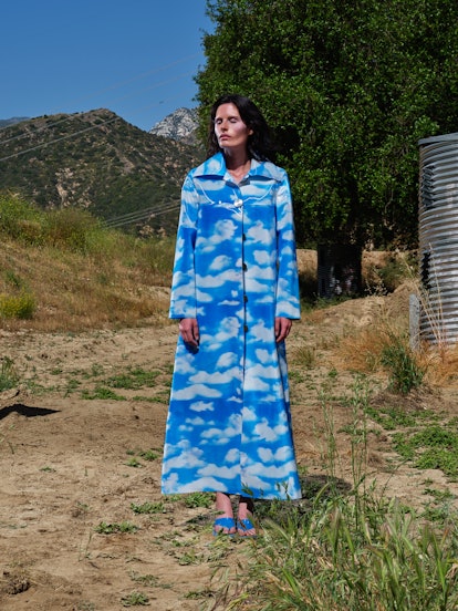 A woman wearing a blue sky coat wit clouds drawn on it