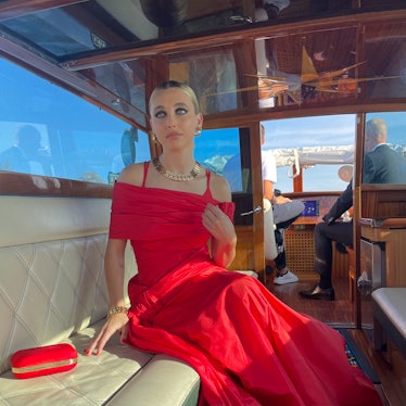 Emma Chamberlain on the water taxi in a red dress during the venice film festival