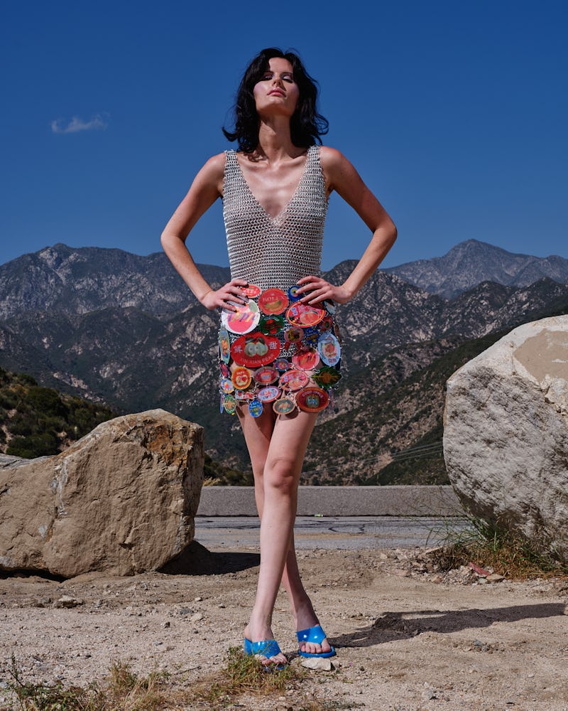 A woman posing in a grey bodysuit and in a colorful skirt
