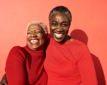 Two female friends dressed in red hugging and smiling.