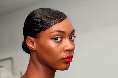 Woman looking at camera with red lipstick and low bun.