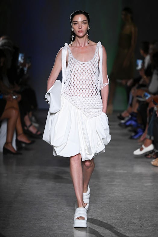 Mariacarla Boscono walks the runway in a loosely knit white tank and a voluminous, knee-length white...