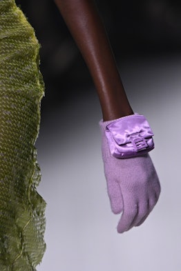 A small purple Baguette bag clipped onto a glove of the same color.