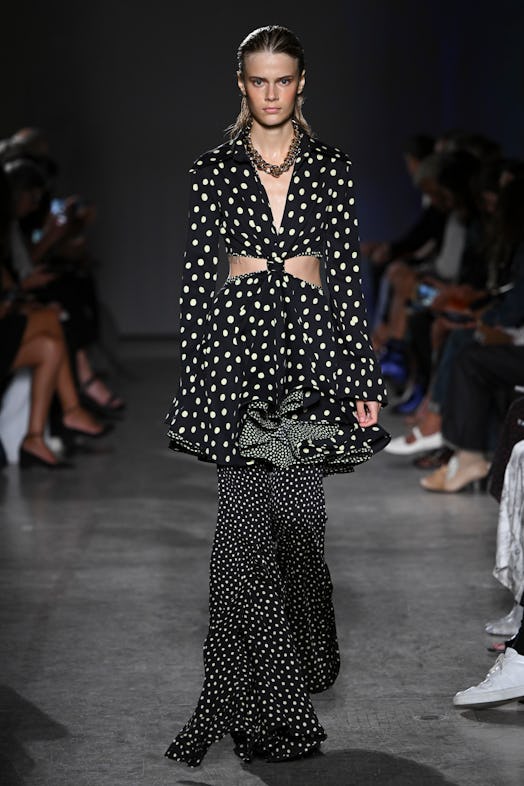 A model wears a layered outfit by Proenza Schouler, adding a polka-dot dress over matching bell-bott...