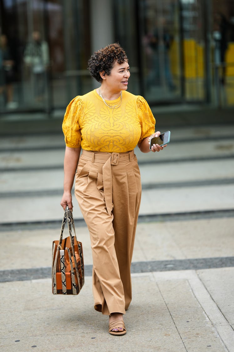 A guest wearing a yellow with flower pattern puffy short sleeves t-shirt, brown wide pants and a big...