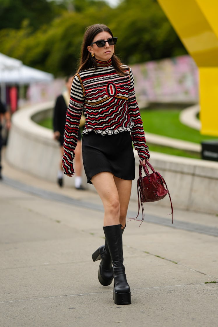 A guest wearing a striped print pattern long t-shirt, a black short skirt and a red shiny Balenciaga...