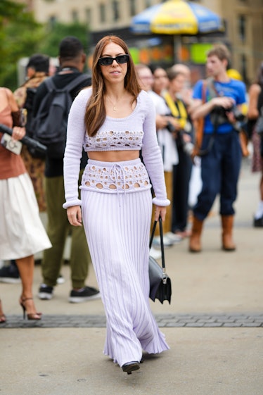 A guest wears black sunglasses, a pale purple cut-out pattern / cropped pullover, a matching pale pu...