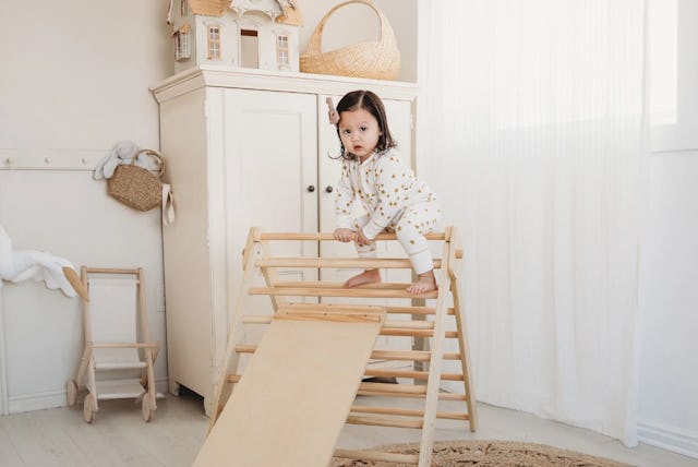 Child sitting on the top of the Piccalio’s wooden climbing toy
