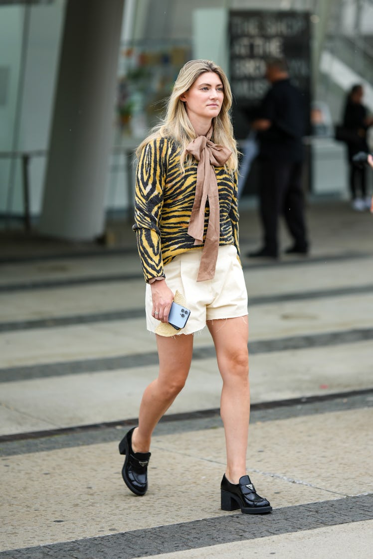 A guest wears a beige silk knot scarf, a yellow and black zebra print pattern long sleeves t-shirt, ...
