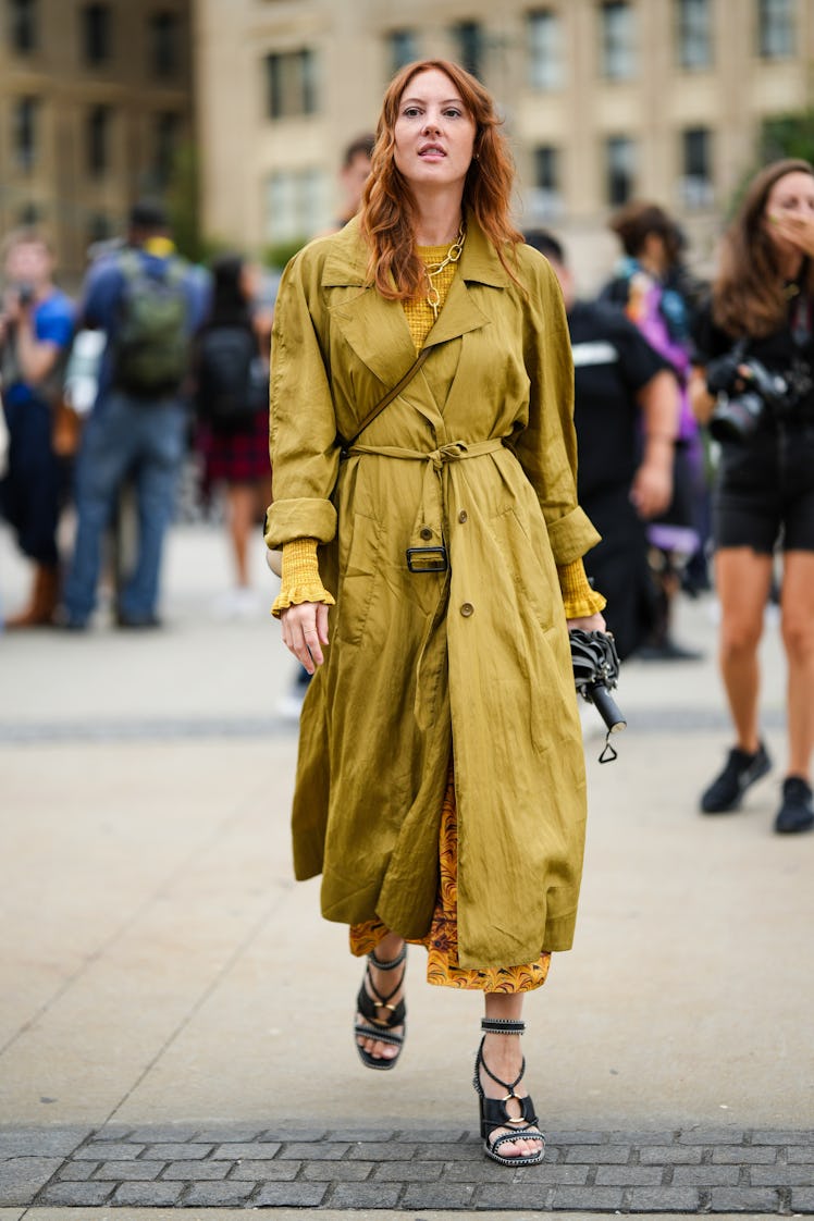 A guest wearing a yellow embossed checkered pattern pullover, a khaki belted long trench coat and a ...