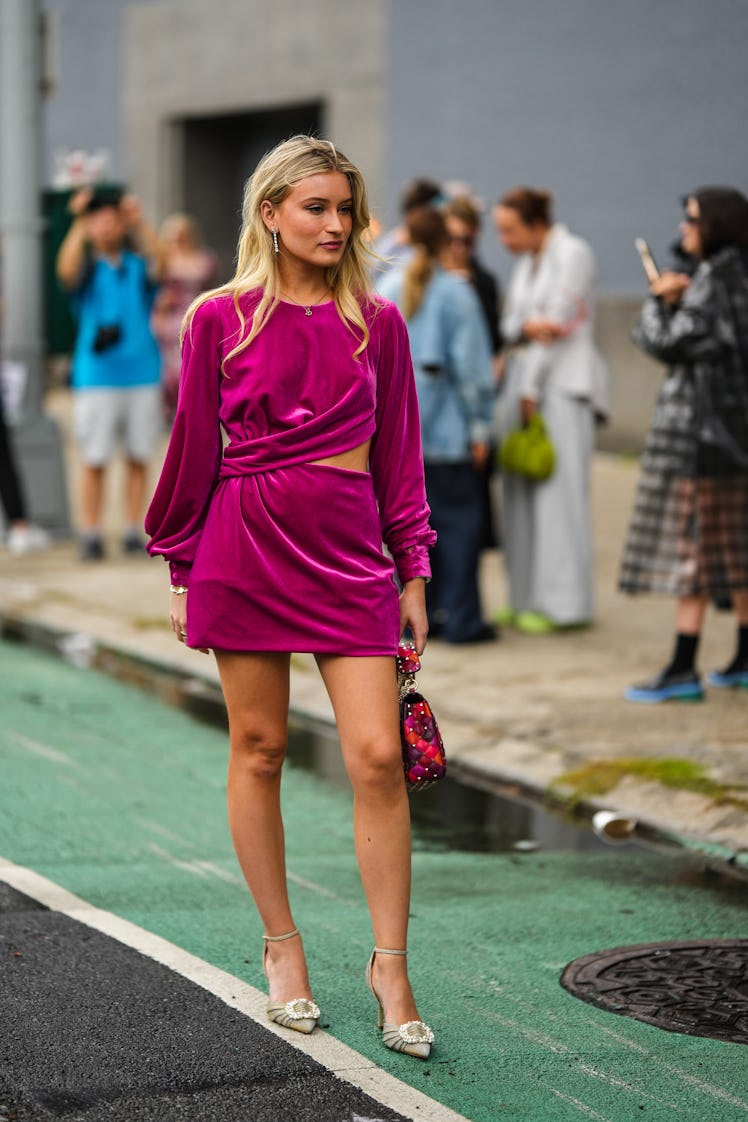 A guest wearing diamonds pendant earrings and necklace, a neon purple velvet short dress and a Valen...