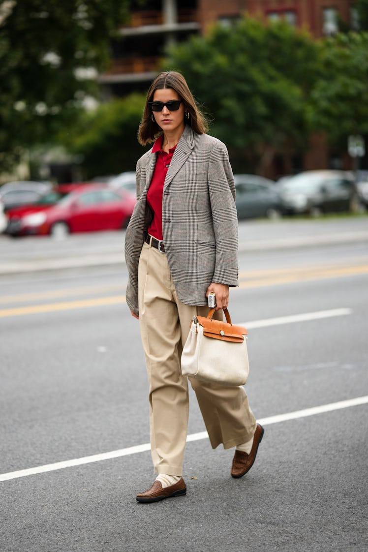 A guest wearing a red polo shirt, a gray print pattern blazer jacket with beige large pants and came...