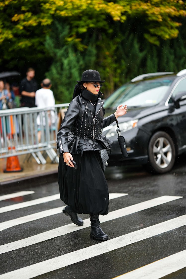 A guest wearing a black felt hat, black sunglasses, a black turtleneck pullover, leather jacket, puf...