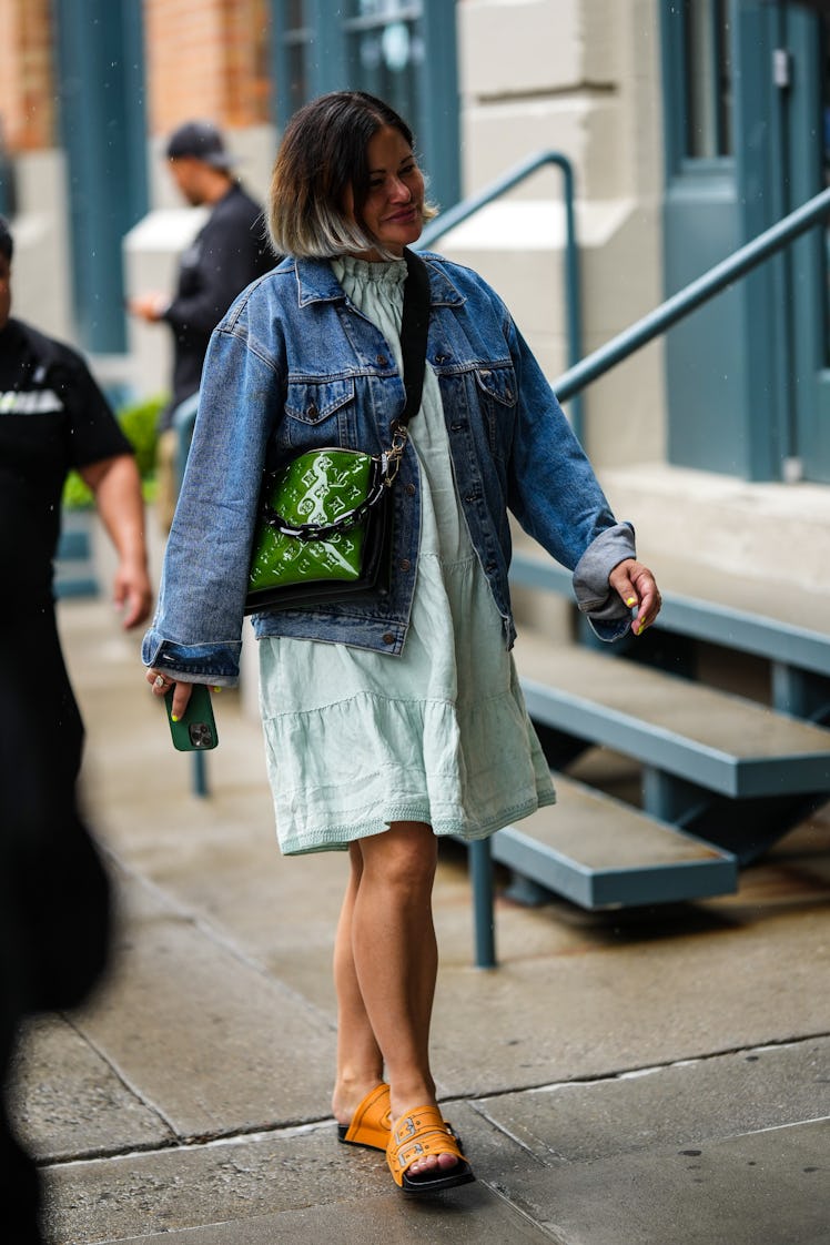 A guest wearing a pale blue ruffled short dress, a green varnished leather Louis Vuitton bag and a l...