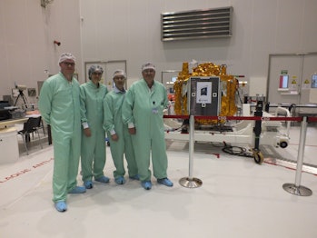 technicians stand by a satellite in a clean room