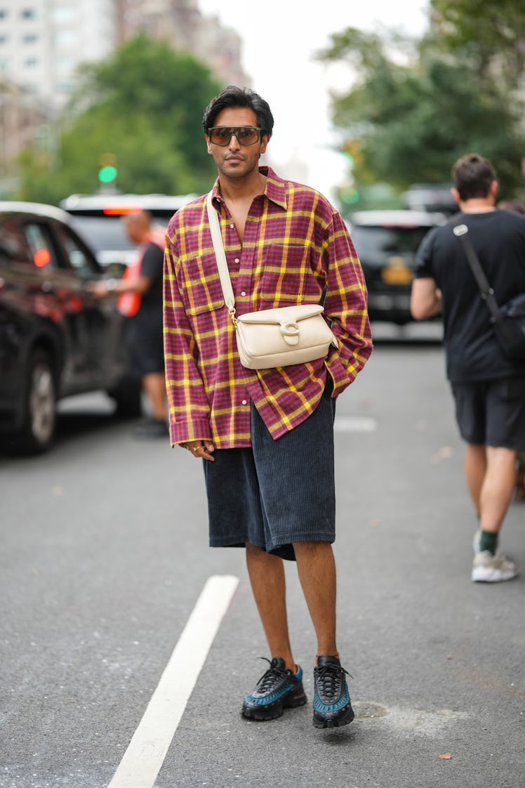Rahi Chadda wearing brown sunglasses, a red and yellow plaid oversized shirt, a Coach bag and a blac...