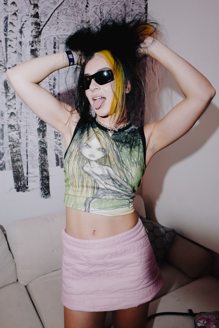 Charli XCX posing in a green top and pink skirt