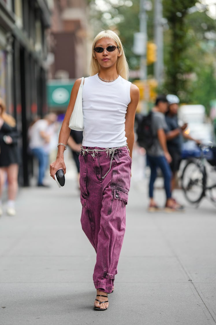 Vanessa Hong wearing black sunglasses, a white tank-top, shoulder bag, a silver chain and purple den...