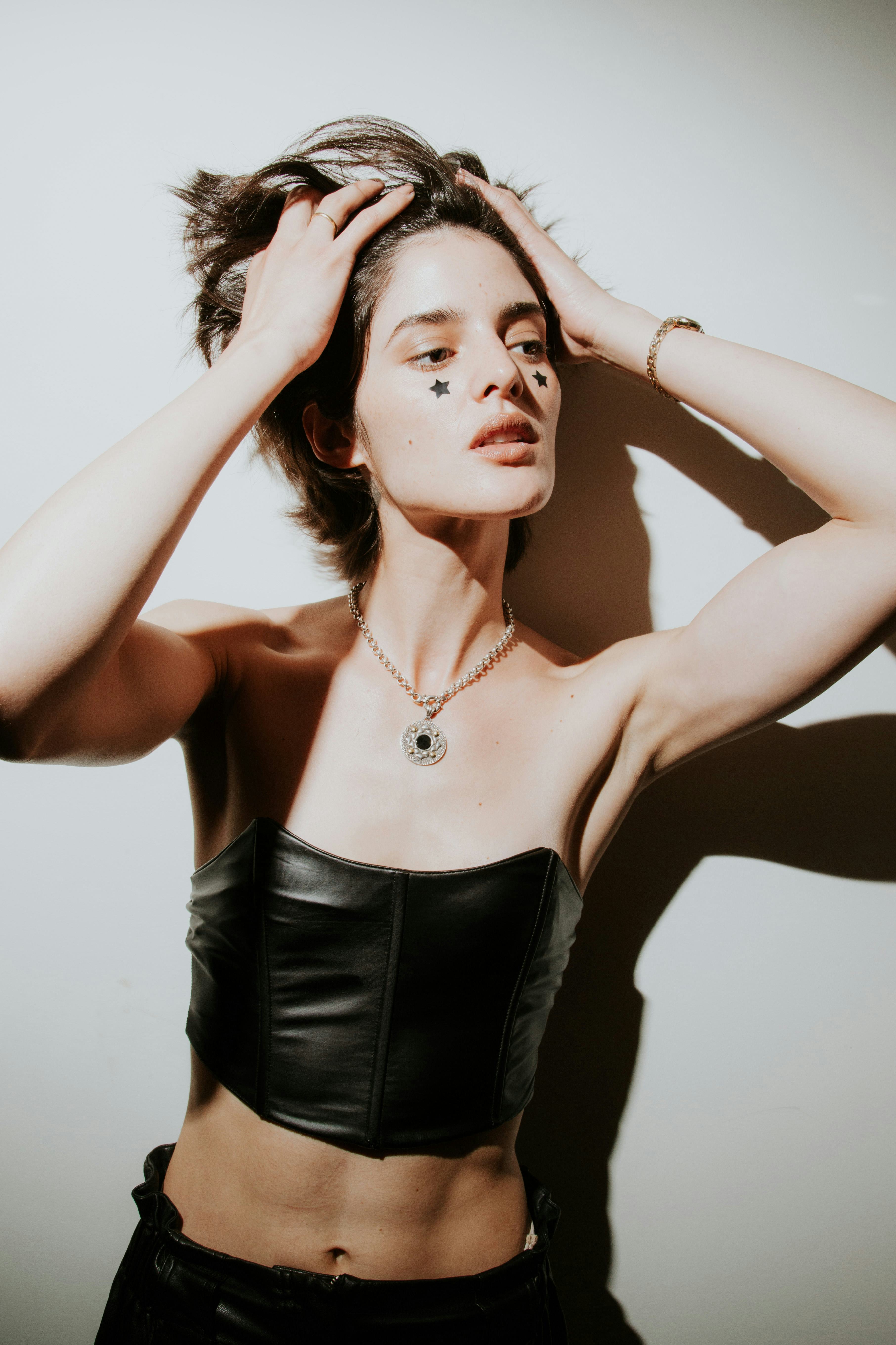 A model with stick on stars under her eyes in a black outfit and flashy necklace